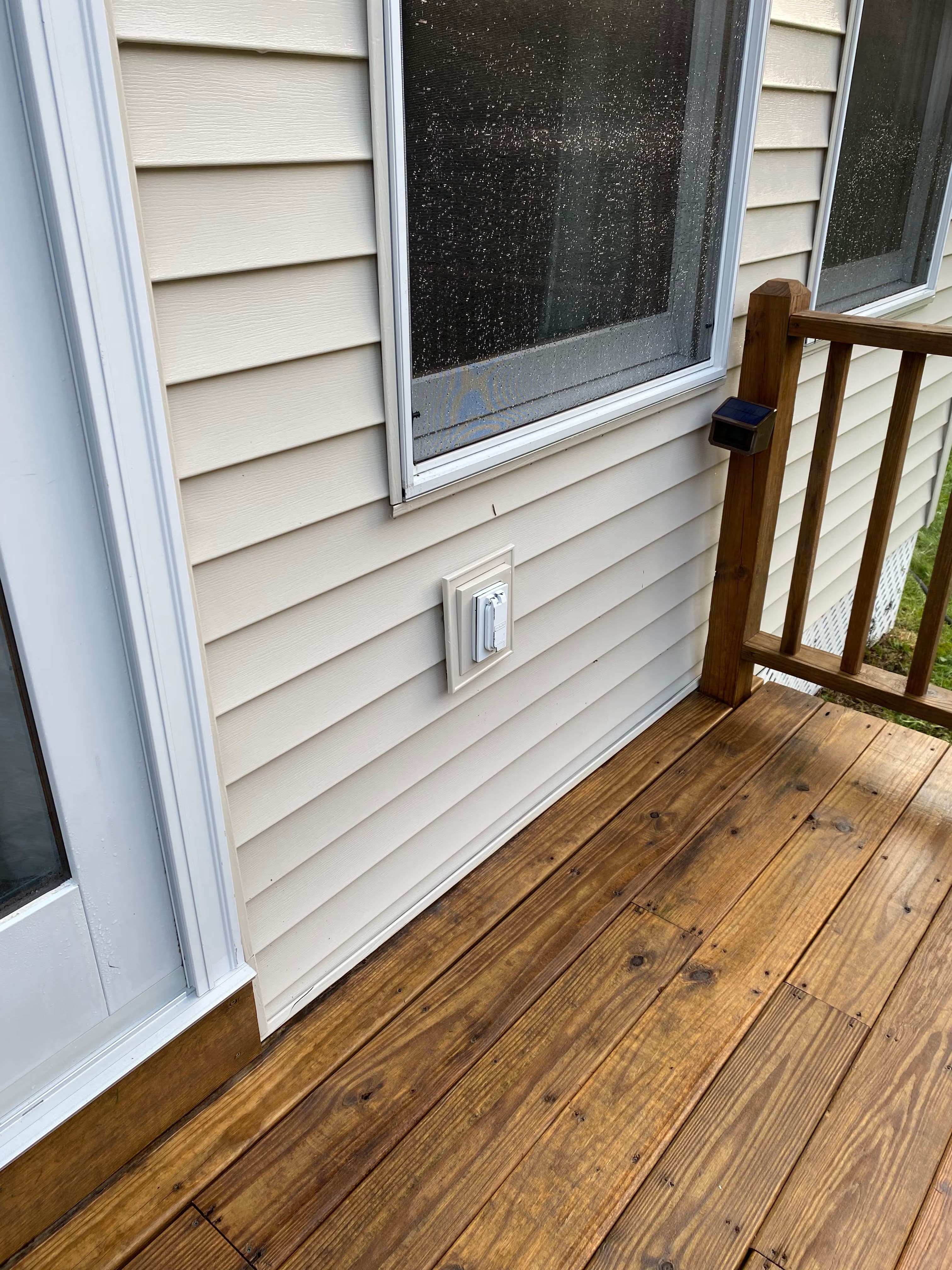 Exterior view of a house showing a cable outlet on a wooden deck.