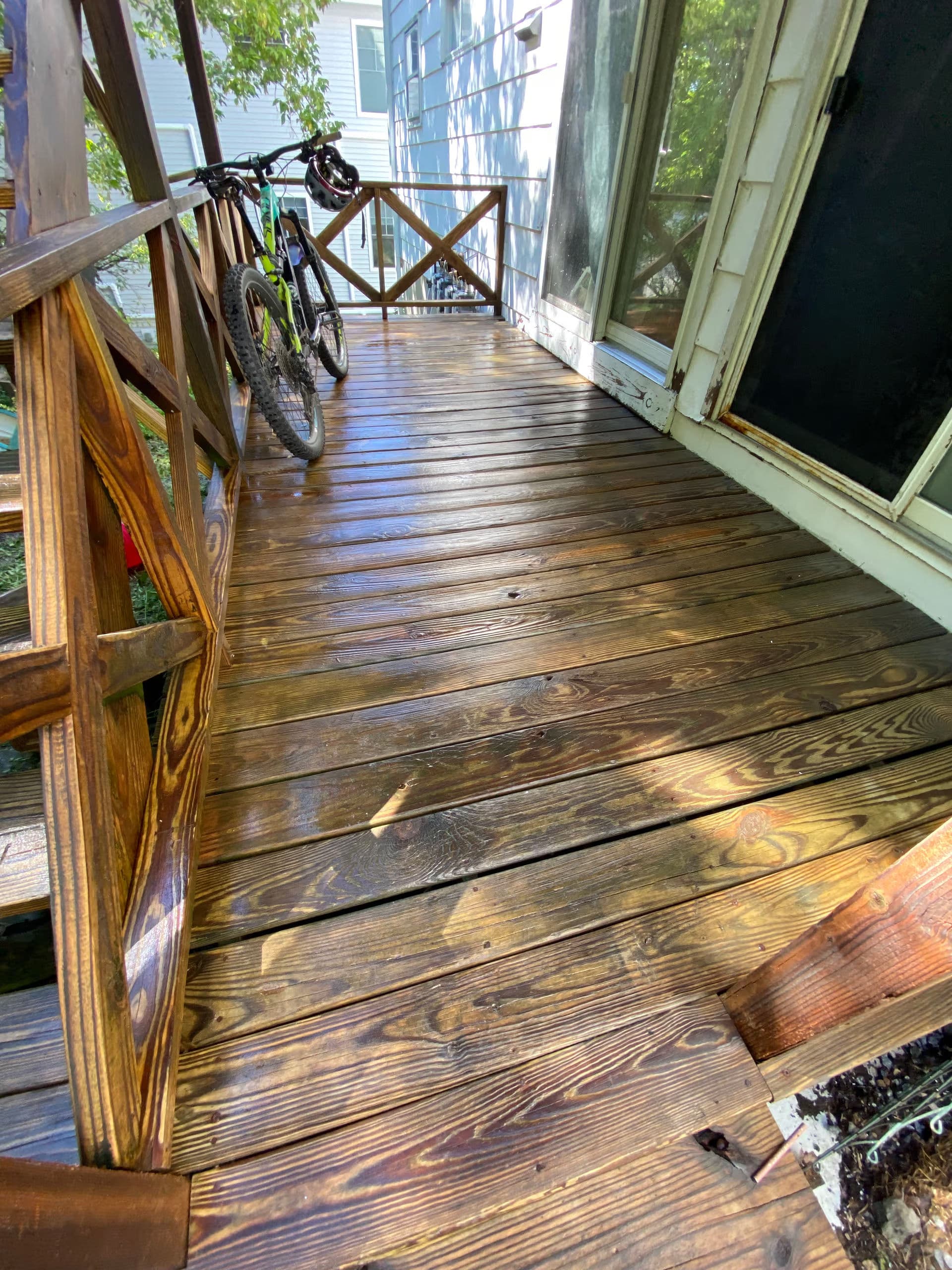 Wooden porch with bikes parked, sunlight reflecting on the polished surface.